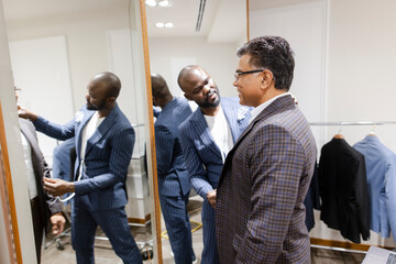 Male tailor measuring customer for suit in menswear shop