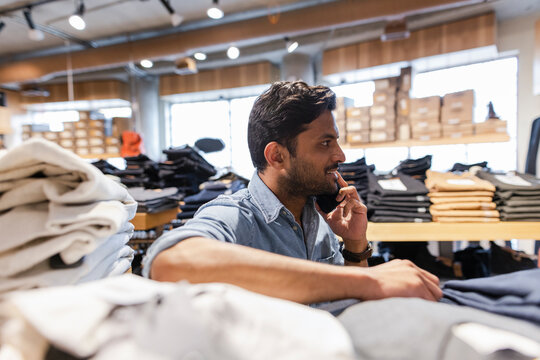 Man talking on smart phone in clothing store