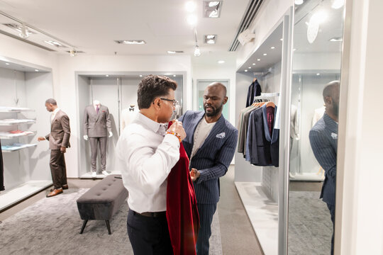 Tailor helping customer with velvet suit in menswear shop