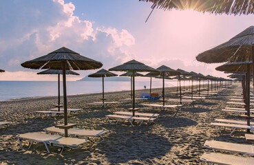 Empty beach with sun loungers and umbrellas in the early morning on a sunny day on the Crete island Greece. High quality photo