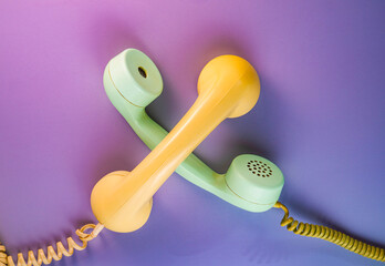 Yellow and green crossed telephone receivers with twisted cords from an old antique rotary phones...