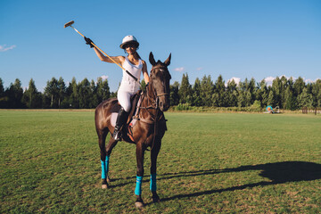Female jockey riding horse on field