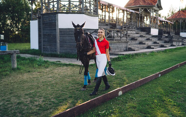 Positive female rider walking on grassy pathway with horse