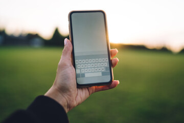 Crop person using cellphone in grassy field