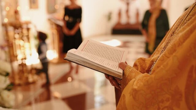 Khmelnytskyi, Ukraine - 09.19.2020: holy father priest in church holds bible book in his hands, reads prayer, turns pages. worship, divine service church, chapel, ministration. clothes cassock