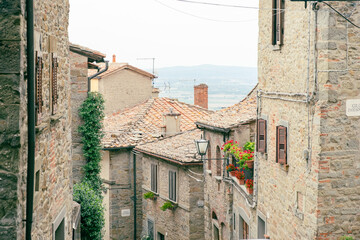 View to impressive ancient cobblestone street with ancient stone buildings and with blue sky and mountain landscape in the background, hedonic leisure