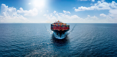 Aerial front view of a container cargo vessel traveling over the ocean with copy space as a banner...