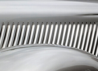 a close up of the bonnet and wheel arch of a silver grey classic 1930s automobile with curved...