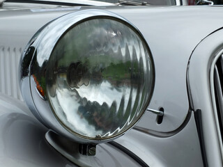close up of the headlamp of an elegant silver colored stylish 1930s vintage automobile