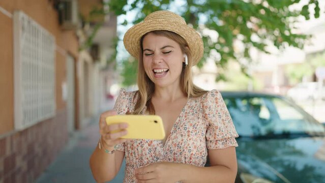Young woman tourist wearing summer watching video on smartphone at street