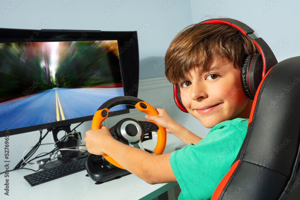 Wall mural Smiling gamer teen boy hands on steering wheel play race game