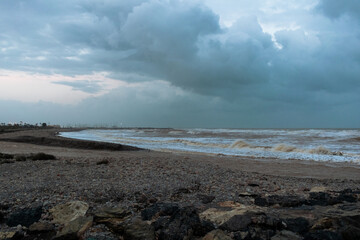 View of Sagunto beach with the rough sea with big waves after the storm under a dramatic sky. Puerto de Sagunto - Valencia
