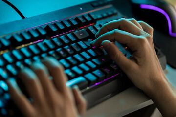 Manos en teclado moderno luminoso de colores