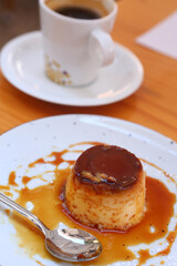  spanish flun pudding dessert closeup photo with teaspoon and cup of coffee on the background