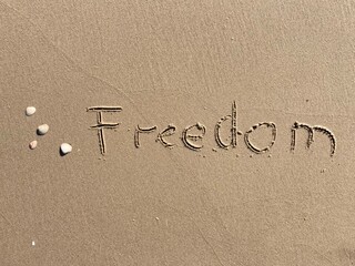 on the beach is carved with letters in the smooth sand the writing freedom