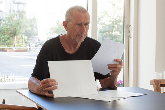 Man reading paper documents while sitting at table.
