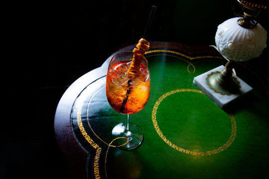 Orange cocktail spritzer on elegant antique table in dark moody atmosphere