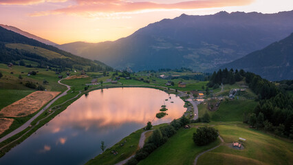 Aerial view at sunrise of lake Wolfsee in Fiss (Tirol, Austria) in summer, on the background the Austrian alps