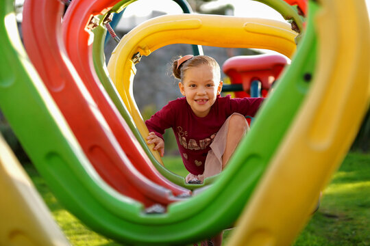 Ni&ntilde;a hermosa rubia latina feliz alegre jugando divertida cruzando un &aacute;rea de juegos en el parque al exterior al aire libre en un hermoso d&iacute;a soleado