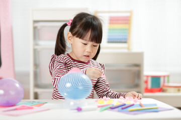 young girl making balloon craft for home schooling