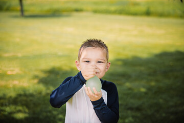 Boy holding a water balloon in the summer time