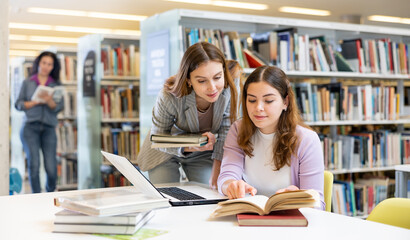 Portrait of two smiling woman working in university library