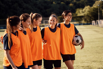 Embraced female soccer players on playing field.