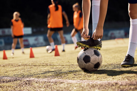 Close up of soccer player tying her shoelaces on playing field. - Powered by Adobe