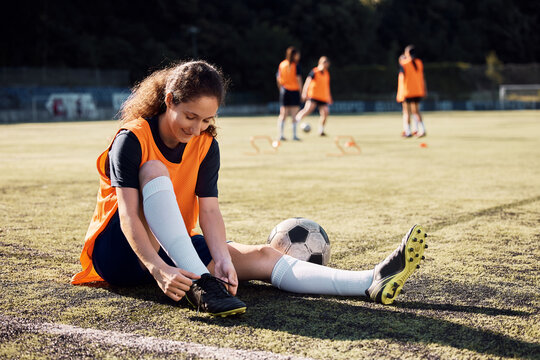 Female player tying shoelace during soccer training on stadium. - Powered by Adobe