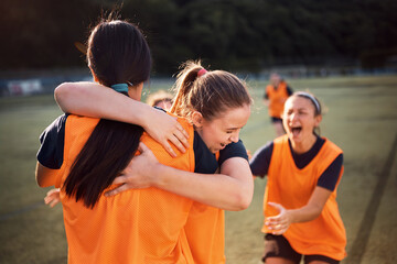 Naklejka premium Happy soccer player embracing her teammate after scoring a goal during match.