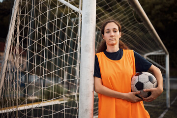Portrait of female soccer player with ball looking at camera.