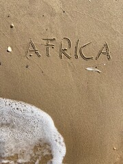 on the beach is carved with letters in the smooth sand the writing Africa