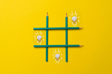 simple creative idea of drawn paper light bulbs in the tic tac toe grid made of crayons on pastel background