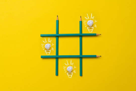 simple creative idea of drawn paper light bulbs in the tic tac toe grid made of crayons on pastel background
