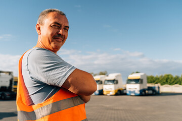 Portrait of caucasian mature man on semi-truck vehicles parking background. Truck driver worker 