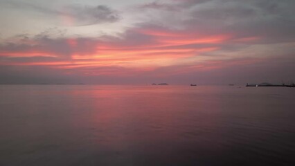 Flying low over calm coastal waters under pink sky at dawn