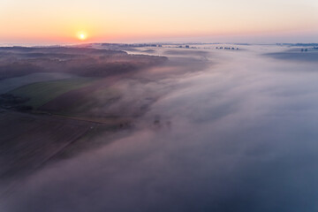 Fototapeta na wymiar Thick fog spreading over green farm fields in Roztocze Poland during colorful sunrise. Morning landscape. Horizontal shot. High quality photo