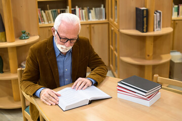 Senior man reading book in the library