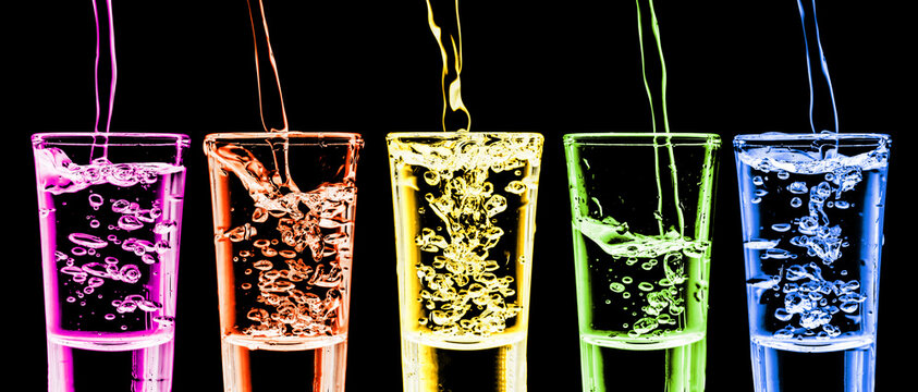Rainbow vodka background. Five vodka shots in a row. Transparent alcohol glass background. Pouring cold vodka. Color liquor backgroud. Booze splashing into glass. Fizzy bubble party isolated on black.