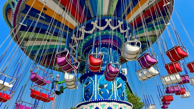 swing chain on which empty seats spin Preparing the park for work Checking the swing for serviceability Expectation of joy and happiness against the background of the sky All the colors of rainbow