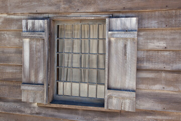 window with bars in wooden wall  