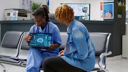 Female nurse and patient looking at human brain analysis on laptop, explaining tomography scan and neural system diagnosis. Specialist and person doing neurology consutation in reception lobby.