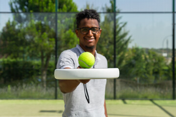 Black tennis player balancing ball on racket 