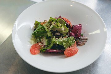 Vegan vegetable salad with grapefruit and cucumber on white plate of kitchen restaurant