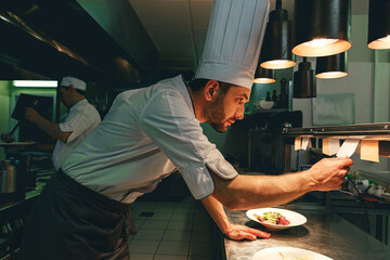 Handsome Chef cook in uniform checking the order at the restaurant kitchen