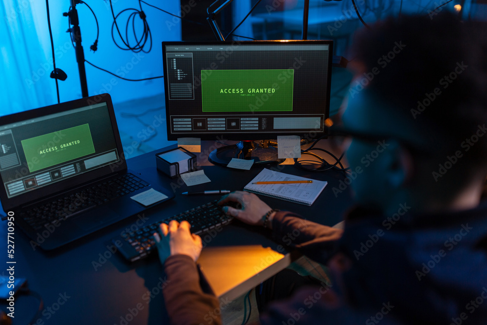 Poster cybercrime, hacking and technology concept - close up of male hacker in dark room writing code or us