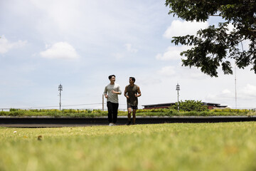 Asian young man jogging together in green park. Concept for healthy lifestyle and oudoor life.