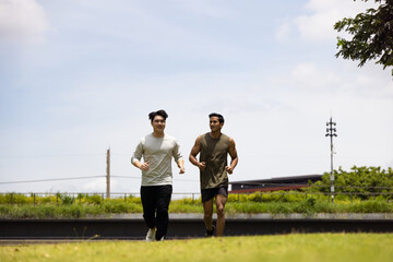 Fototapeta premium Asian young man jogging together in green park. Concept for healthy lifestyle and oudoor life.