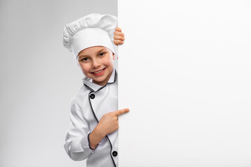 cooking, culinary and profession concept - happy smiling little boy in chef's toque and jacket with white board over grey background