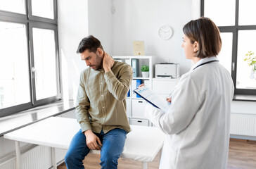 medicine, healthcare and people concept - male patient with pain in neck and female doctor at medical office in hospital